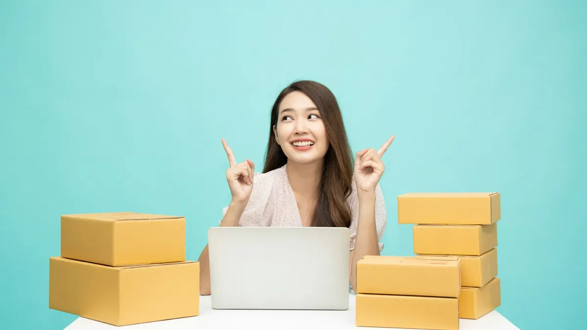 A person at a laptop surrounded by parcels, working on online orders