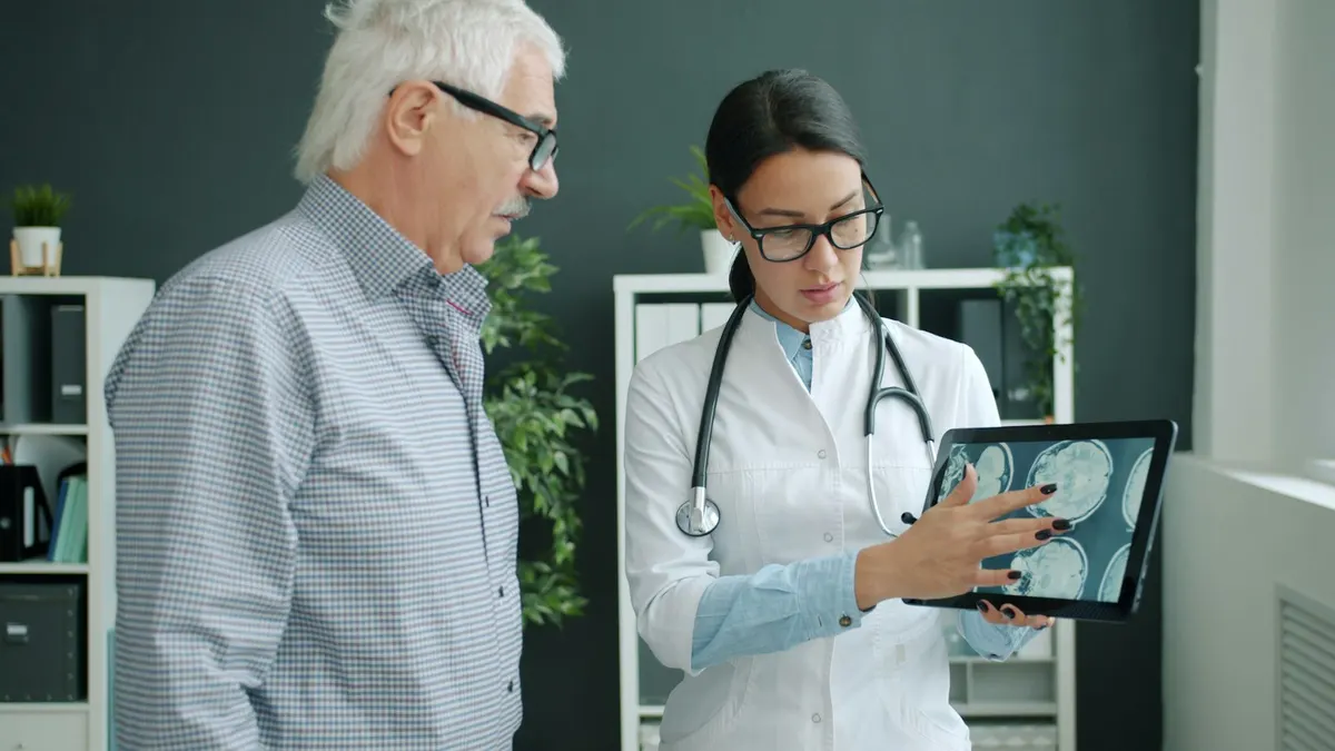 A doctor reviewing a scan on a tablet with a patient in a clinic