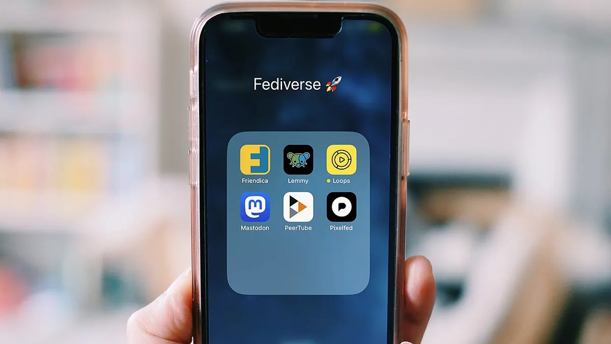 A hand holding a smartphone with a folder of apps open