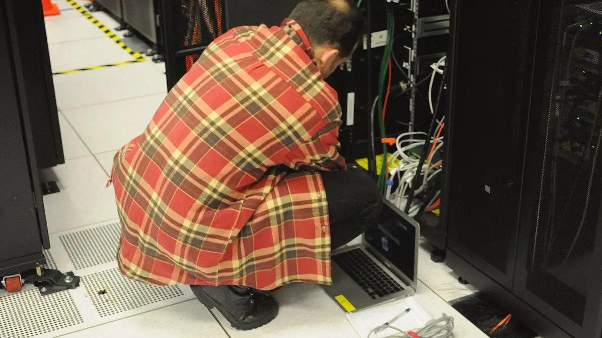 Technician working on a laptop at a server rack